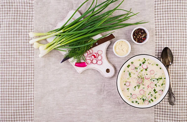 Cold soup with fresh cucumbers, radishes, potato and sausage with yoghurt in bowl. Traditional russian food - okroshka. Summer cold soup. Top view. Flat lay