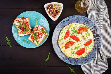 Domates, jambon, yeşil soğan ve koyu masa üzerinde çilek ile sandviç ile Omlet. Frittata - İtalyan omlet. Üstte görüntü