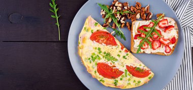 Koyu masada domates, jambon ve yeşil soğan ile Omlet. Frittata - İtalyan omlet. Üstte görüntü