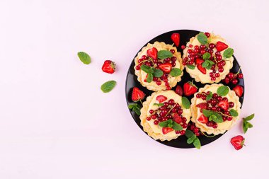 Çilek, kuş üzümü ve nane yaprakları ile süslenmiş krem şanti ile Tarts. Üstte görüntü