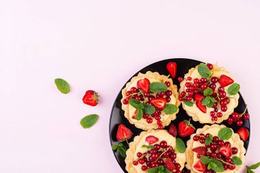 Çilek, kuş üzümü ve nane yaprakları ile süslenmiş krem şanti ile Tarts. Üstte görüntü