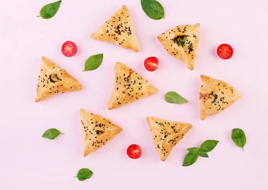 Asya yemekleri. Samsa (samosa) tavuk fileto ve pembe arka plan üzerinde yeşil otlar ile. Üstte görüntü