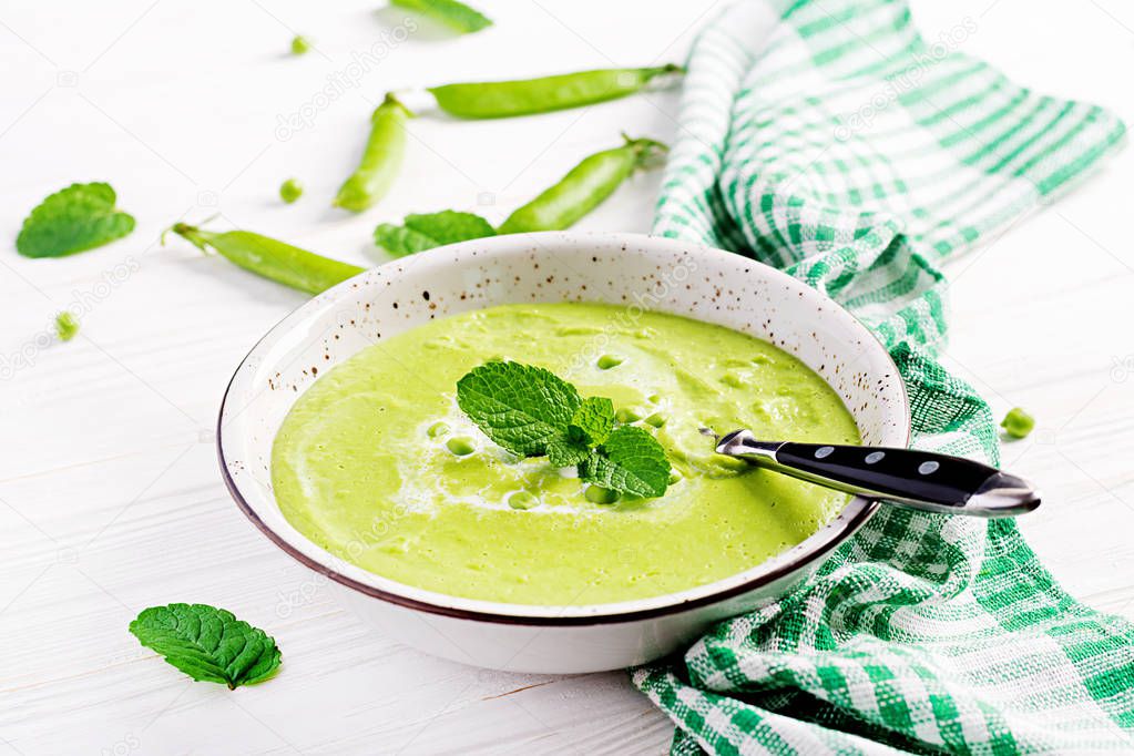 Green pea soup in bowl on wooden table. French cuisine.