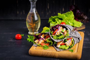 Tortilla ile eklenen mürekkep mürekkepbalığı siyah arka planda tavuk ve sebze ile sarar. Tavuk burrito, Meksika yemekleri.