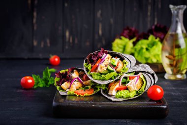 Tortilla ile eklenen mürekkep mürekkepbalığı siyah arka planda tavuk ve sebze ile sarar. Tavuk burrito, Meksika yemekleri.