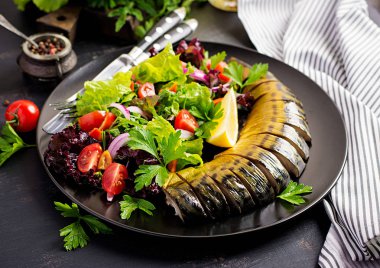 Koyu arka planda füme uskumru ve taze salata.