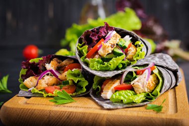 Tortilla ile eklenen mürekkep mürekkepbalığı siyah arka planda tavuk ve sebze ile sarar. Tavuk burrito, Meksika yemekleri.