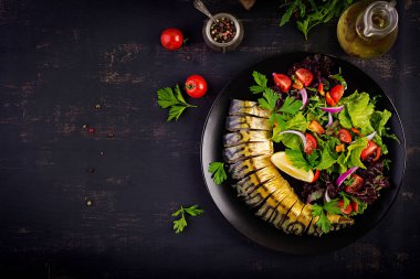 Koyu arka planda füme uskumru ve taze salata. Üst görünüm