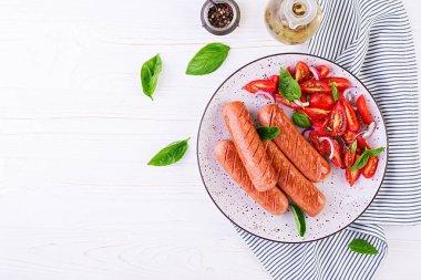 Domates, fesleğen salatası ve kırmızı soğan ile ızgara sosis. Barbekü menüsü. Üstte görüntü