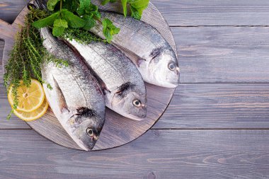 Yeşil otlar kesme tahtası üzerinde pişirme ile Ham dorado balık. Üstte görüntü