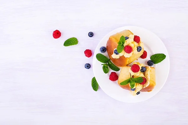 ホイップクリームと新鮮なラズベリー ブルーベリーで飾られたラムババ クリーム ベリーのサヴァリン イタリア料理トップビュー — ストック写真