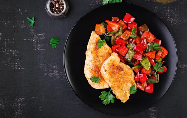 Grilled chicken fillets and sweet pepper on black plate. Top view, copy space