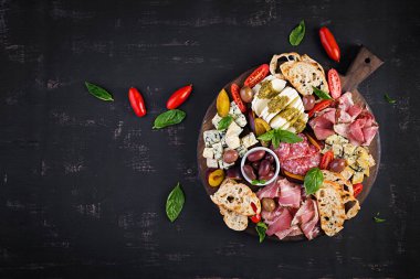 Jambon, prosciutto, salam, mavi peynir, mozzarella pesto ve ahşap bir arka plan üzerinde zeytin ile antipasto tabağı. Üst görünüm, genel merkez