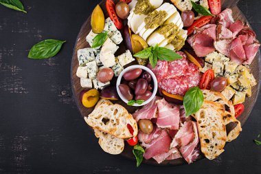 Jambon, prosciutto, salam, mavi peynir, mozzarella pesto ve ahşap bir arka plan üzerinde zeytin ile antipasto tabağı. Üst görünüm, genel merkez