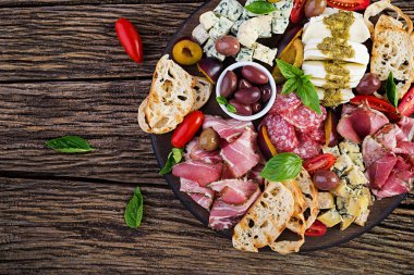 Jambon, prosciutto, salam, mavi peynir, mozzarella pesto ve ahşap bir arka plan üzerinde zeytin ile antipasto tabağı. Üst görünüm, genel merkez