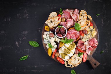 Jambon, prosciutto, salam, mavi peynir, mozzarella pesto ve ahşap bir arka plan üzerinde zeytin ile antipasto tabağı. Üst görünüm, genel merkez