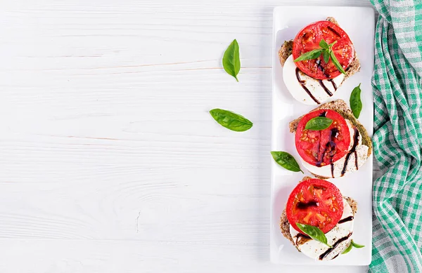 在白色木桌上摆着三明治 包括莫扎雷拉 西红柿和黑麦面包 顶部视图 — 图库照片