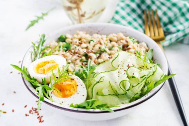Yeşil otlu yulaf lapası, haşlanmış yumurta, salatalık ve keten tohumu. Sağlıklı dengeli yiyecekler.