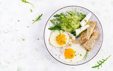 İngiliz kahvaltısı. Yağda yumurta, peynir, salatalık ve roka. Amerikan yemeği. Üst görünüm, genel görünüm, kopyalama alanı