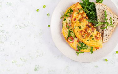 Domatesli omlet, jambon, peynir ve tabakta yeşil otlar. Frittata - İtalyan omleti. Üst görünüm, genel görünüm, kopyalama alanı