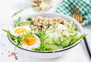 Yeşil otlu yulaf lapası, haşlanmış yumurta, salatalık ve keten tohumu. Sağlıklı dengeli yiyecekler.