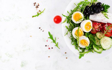 Kahvaltıda. Yunan salatası ve haşlanmış yumurta. Taze sebze salatası, domates, salatalık, zeytin, roka ve peynir. Moda yemeği. Üst manzara, düz uzanma