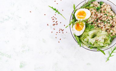 Yeşil otlu yulaf lapası, haşlanmış yumurta, salatalık ve keten tohumu. Sağlıklı dengeli yiyecekler. Üst görünüm, genel görünüm, kopyalama alanı