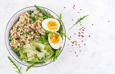 Yeşil otlu yulaf lapası, haşlanmış yumurta, salatalık ve keten tohumu. Sağlıklı dengeli yiyecekler. Üst görünüm, genel görünüm, kopyalama alanı
