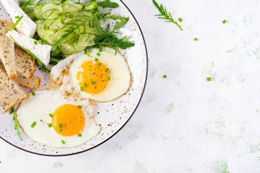 İngiliz kahvaltısı. Yağda yumurta, peynir, salatalık ve roka. Amerikan yemeği. Üst görünüm, genel görünüm, kopyalama alanı