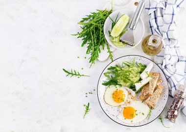 İngiliz kahvaltısı. Yağda yumurta, peynir, salatalık ve roka. Amerikan yemeği. Üst görünüm, genel görünüm, kopyalama alanı