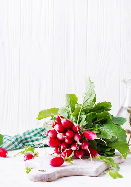 Spring harvest red radish on light background.  Bunch of fresh french breakfast radish. Growing vegetables. Vegetarian food.