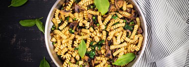 Tavada ıspanaklı ve mantarlı Fusilli makarna. Vejetaryen / vejetaryen yemeği. İtalyan mutfağı. Üst görünüm, pankart, kopyalama alanı