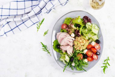 Ketogenik diyet. Haşlanmış domuz eti, avokado guacamole, domates, salatalık, mozzarella peyniri, siyah zeytin ve roka ile akşam yemeği. Detoks ve sağlıklı konsept. Keto yemeği. Yukarıdan, yukarıdan.