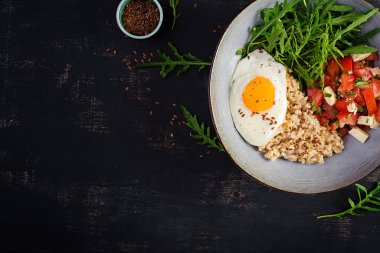 Kahvaltı yulaf lapası, kızarmış yumurta, domates salatası, roka ve keten tohumu. Sağlıklı dengeli yiyecekler. Üst görünüm, genel görünüm, kopyalama alanı