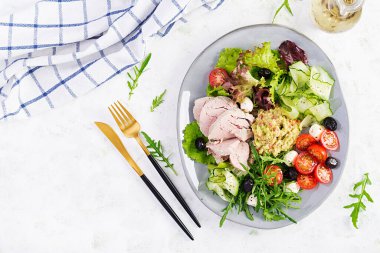 Ketogenik diyet. Haşlanmış domuz eti, avokado guacamole, domates, salatalık, mozzarella peyniri, siyah zeytin ve roka ile akşam yemeği. Detoks ve sağlıklı konsept. Keto yemeği. Yukarıdan, yukarıdan.