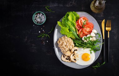 Kahvaltı yulaf lapası, kızarmış yumurta, domates, mozzarella peyniri roka ve kızarmış mantar. Sağlıklı yiyecekler. Üst görünüm, genel görünüm, kopyalama alanı