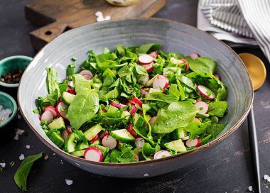 Vejetaryen sebze salatası, turp, salatalık ve ıspanak. Sağlıklı vejetaryen yemekleri.