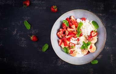 Süzme peynir ya da çilekli peynir, muz, mavi kasede ceviz. Sağlıklı yiyecekler. Üst görünüm, genel görünüm, kopyalama alanı