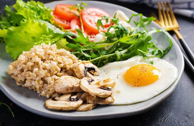 Kahvaltı yulaf lapası, kızarmış yumurta, domates, mozzarella peyniri roka ve kızarmış mantar. Sağlıklı yemek..