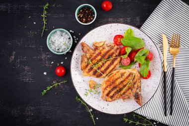 Izgara domuz bifteği ve arka planda domatesli salata. Üst görünüm, genel görünüm, kopyalama alanı