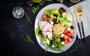 Ketogenik diyet. Haşlanmış domuz eti, avokado guacamole, domates, salatalık, mozzarella peyniri, siyah zeytin ve roka ile akşam yemeği. Detoks ve sağlıklı konsept. Keto yemeği. Yukarıdan, yukarıdan.