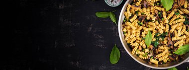 Tavada ıspanaklı ve mantarlı Fusilli makarna. Vejetaryen / vejetaryen yemeği. İtalyan mutfağı. Üst görünüm, pankart, kopyalama alanı