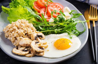 Kahvaltı yulaf lapası, kızarmış yumurta, domates, mozzarella peyniri roka ve kızarmış mantar. Sağlıklı yemek..