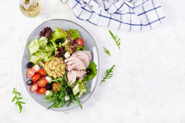 Ketogenik diyet. Haşlanmış domuz eti, avokado guacamole, domates, salatalık, mozzarella peyniri, siyah zeytin ve roka ile akşam yemeği. Detoks ve sağlıklı konsept. Keto yemeği. Yukarıdan, yukarıdan.