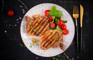 Izgara domuz bifteği ve arka planda domatesli salata. Üst görünüm, genel görünüm, kopyalama alanı