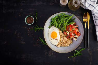 Kahvaltı yulaf lapası, kızarmış yumurta, domates salatası, roka ve keten tohumu. Sağlıklı dengeli yiyecekler. Üst görünüm, genel görünüm, kopyalama alanı