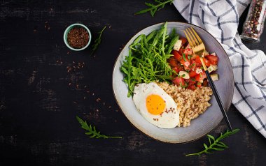 Kahvaltı yulaf lapası, kızarmış yumurta, domates salatası, roka ve keten tohumu. Sağlıklı dengeli yiyecekler. Üst görünüm, genel görünüm, kopyalama alanı