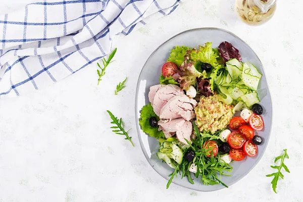 Ketogenik diyet. Haşlanmış domuz eti, avokado guacamole, domates, salatalık, mozzarella peyniri, siyah zeytin ve roka ile akşam yemeği. Detoks ve sağlıklı konsept. Keto yemeği. Yukarıdan, yukarıdan.