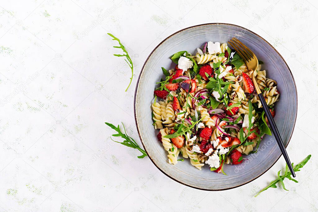 Pasta salad. Fusilli Pasta - salad with strawberry, feta cheese, red onion and balsamic sauce. Top view, flat lay, copy space