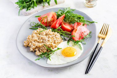 Kahvaltı yulaf lapası, sahanda yumurta, domates ve roka. Sağlıklı yemek..